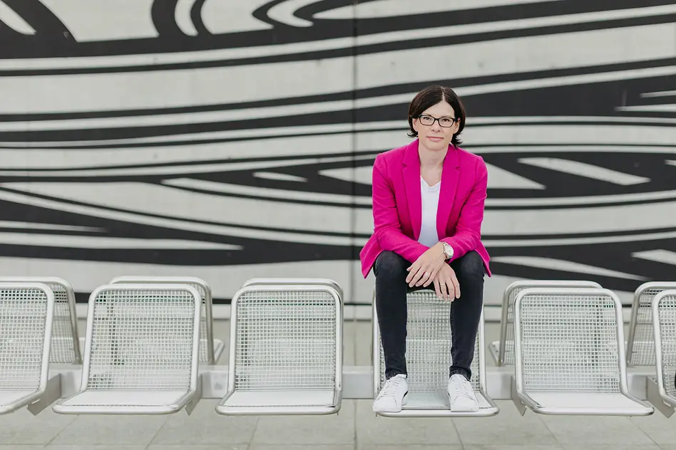 Personal Branding Fotografie einer Unternehmerin sitzend in moderner Architektur mit grafischem Hintergrund