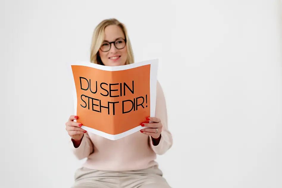 Personal Branding Fotografie einer Unternehmerin, die ein Schild mit der Aufschrift „Du sein steht dir“ hält